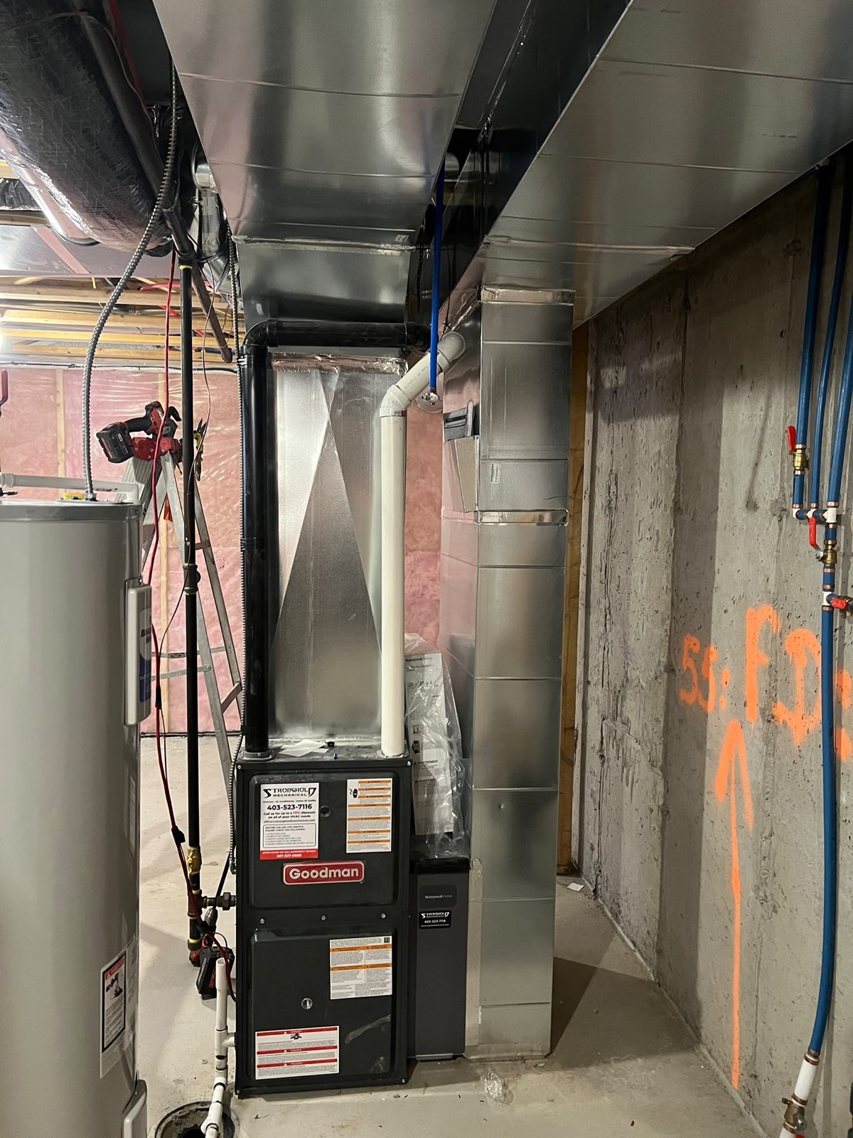 New furnace and hot water tank installed side by side in a mechanical room